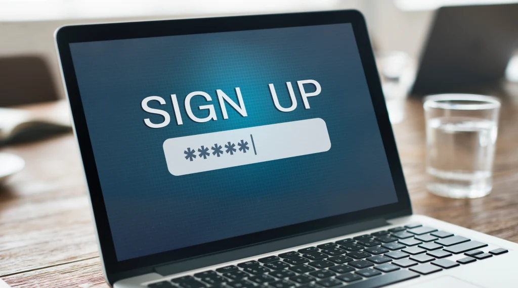 A person signing up on a laptop, using a keyboard and mouse for input.