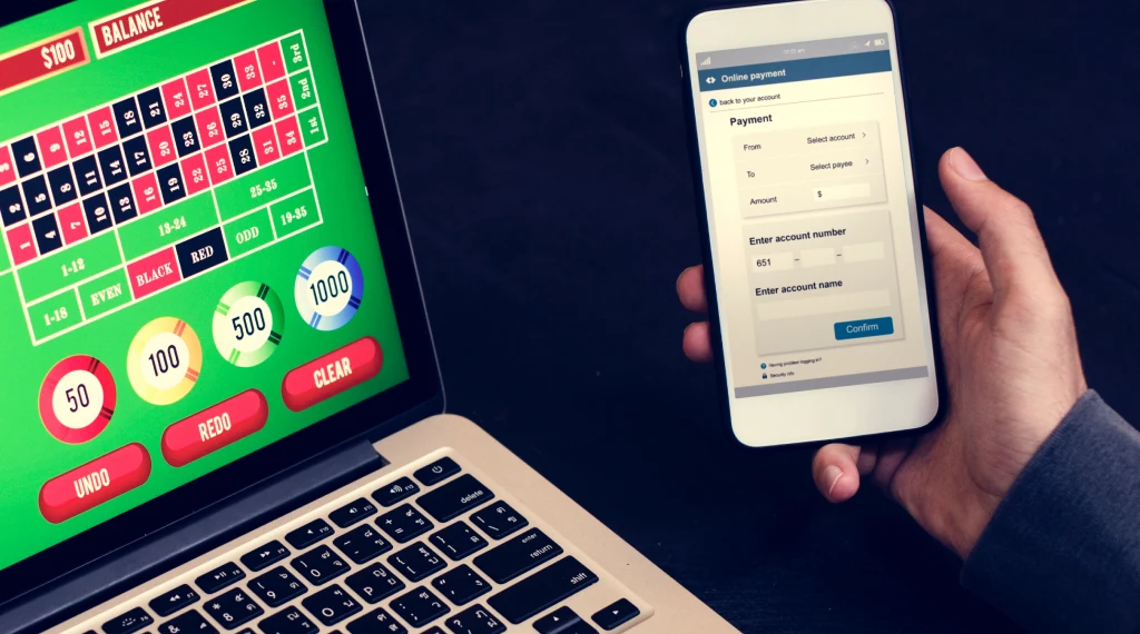 User making an online Bitcoin deposit on a mobile device while engaging in a roulette game on a laptop.