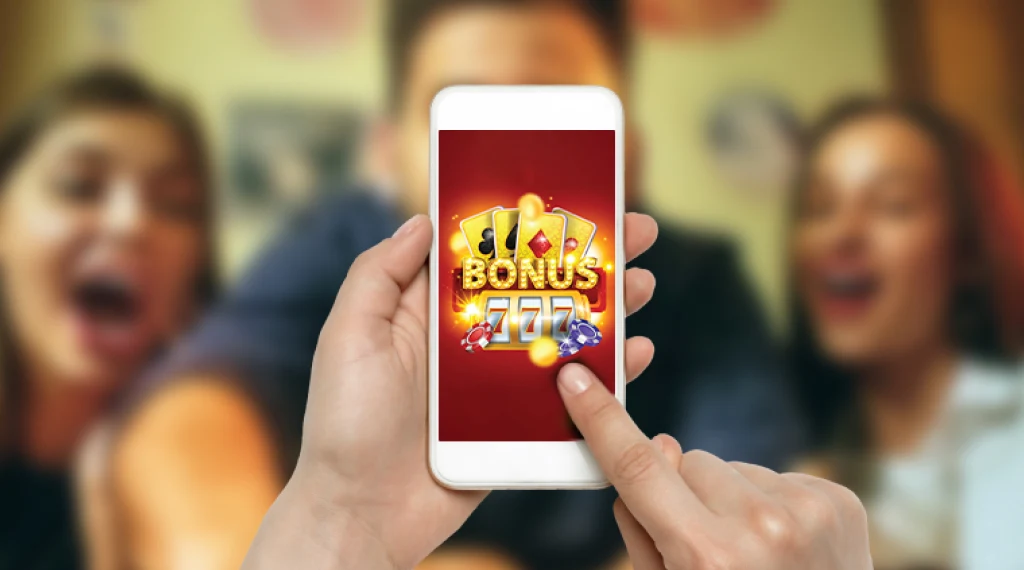 Person using a smartphone displaying a bonus-themed casino game, with excited friends in the background