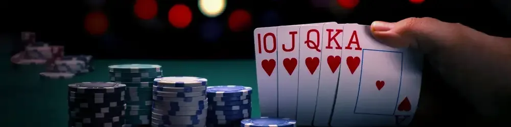 Poker hand with chips in dim casino background.