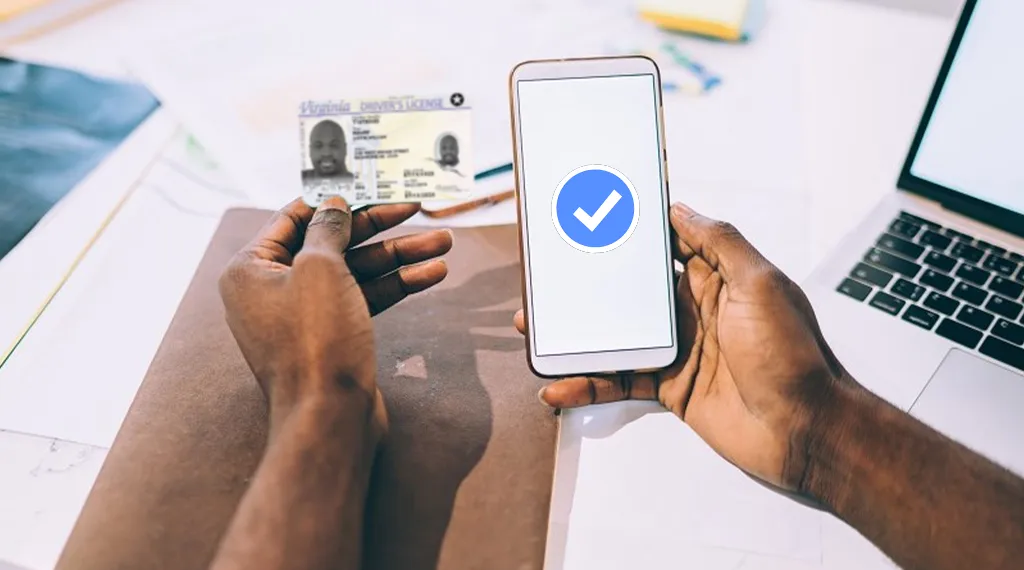 A person holding a driver's license while verifying their identity through a smartphone.