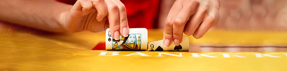 A person holds a card above a table scattered with various other cards.