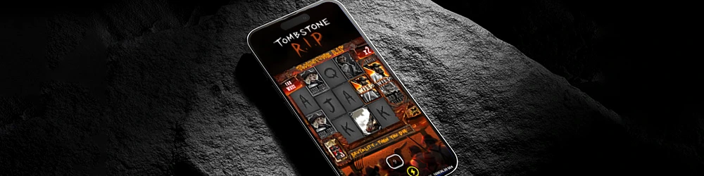 A mobile phone displaying the Tombstone RIP game with a dark, intense background, showcasing the reels of the game with symbols like skulls, guns, and cards, embodying the western, eerie theme of the game.