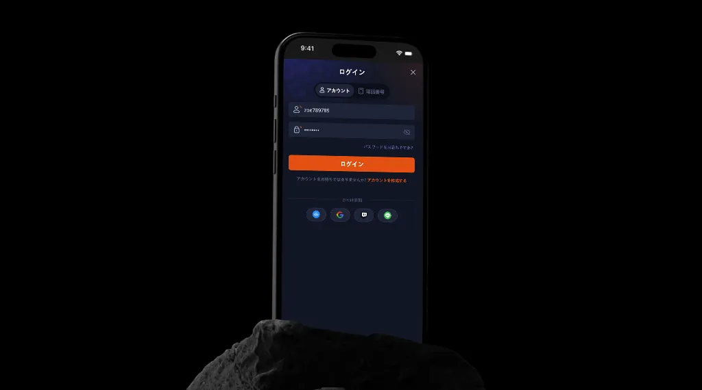 スマートフォンの画面に表示されたログイン画面。ユーザー名とパスワードを入力するフィールドがあり、ログインボタンがオレンジ色で強調されています。下にはGoogleとTwitchのアイコンが表示されています。