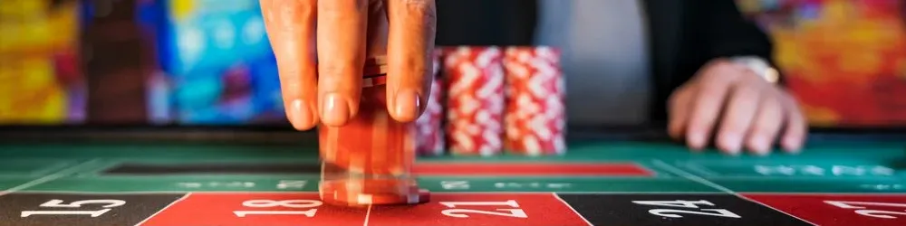 A person focused on playing roulette at a casino table, with chips and a spinning wheel in view.