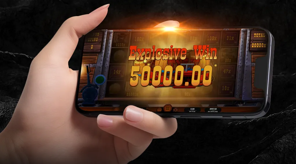 A hand raises a smartphone showing the phrase "the ultimate win" from the Money Train game.